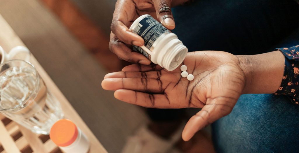 Imagem de uma mão segurando várias pílulas de remédio, simbolizando cuidado com a saúde e tratamento médico. Compreenda a importância da medicação e gestão da saúde para um estilo de vida equilibrado.